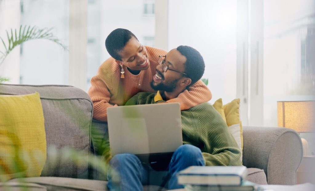 Smiling couple relaxing on a sofa with a laptop.