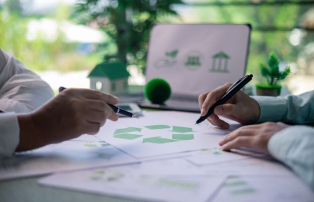 Hands holding pens over documents with green symbols