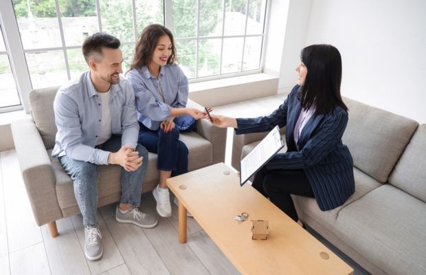 Couple receiving documents from a woman in office