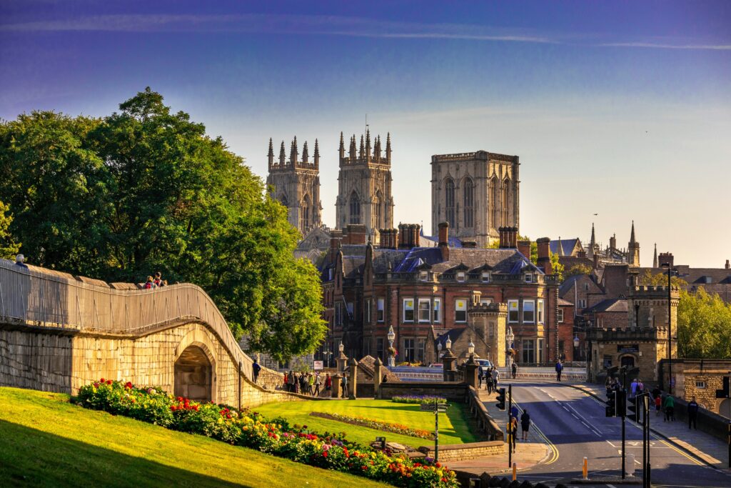 View of York’s medieval city walls, lush gardens, and the iconic York Minster towers on a sunny day.