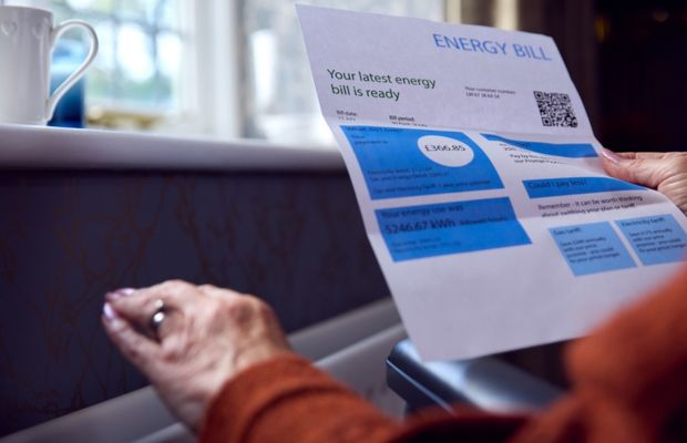 Person holding an energy bill document indoors