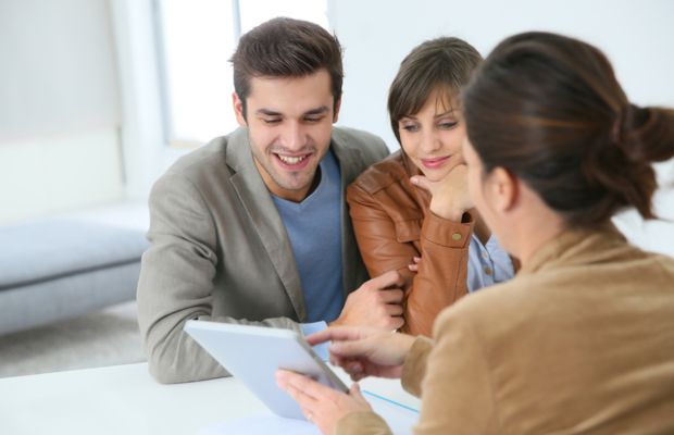 Three people discussing over tablet at a table