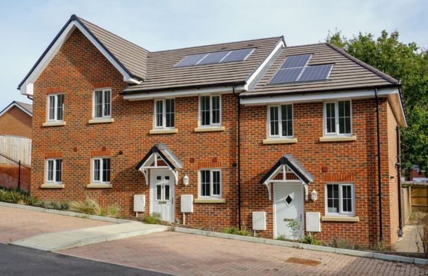 Two-story brick house with solar panels and driveway.