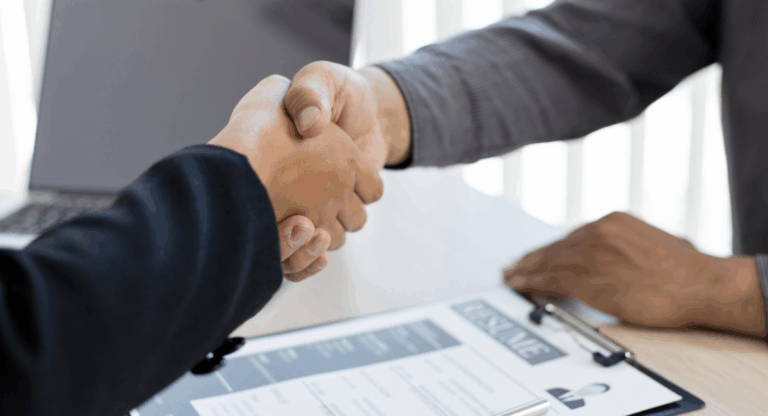 Two people shaking hands over a property rental agreement with a CV and paperwork on the table, symbolising a Worksop landlord and tenant deal