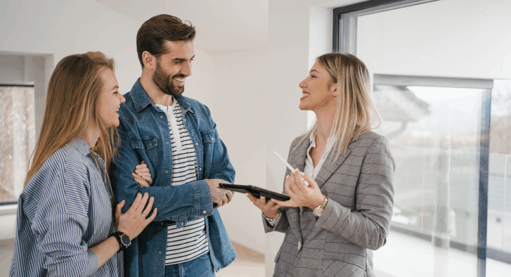 Smiling estate agent talking to a couple during a property viewing, representing Martin & Co’s 2025 guide to simple home improvements that attract buyers.