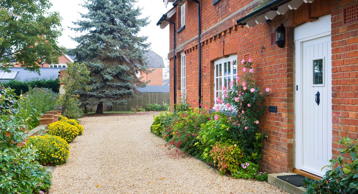 Front view of a traditional red brick home with a tidy gravel driveway and flowers, representing Martin & Co’s 2025 guide to successful property management for landlords.
