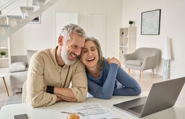 Couple smiles together while looking at a laptop