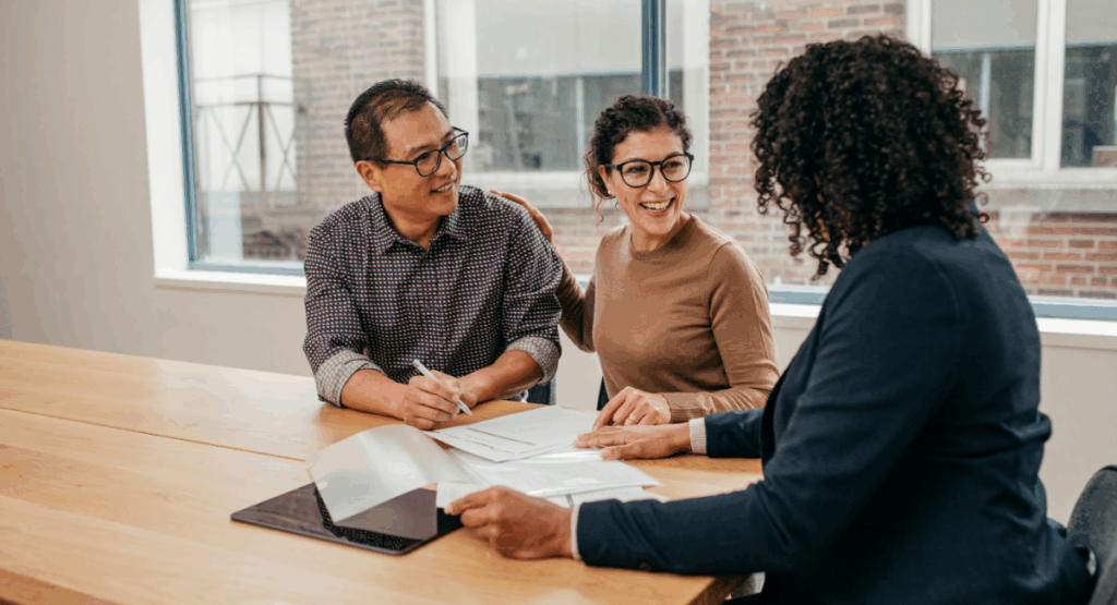 A landlord meeting with tenants to review property documents and discuss winter maintenance preparations in a bright office setting.