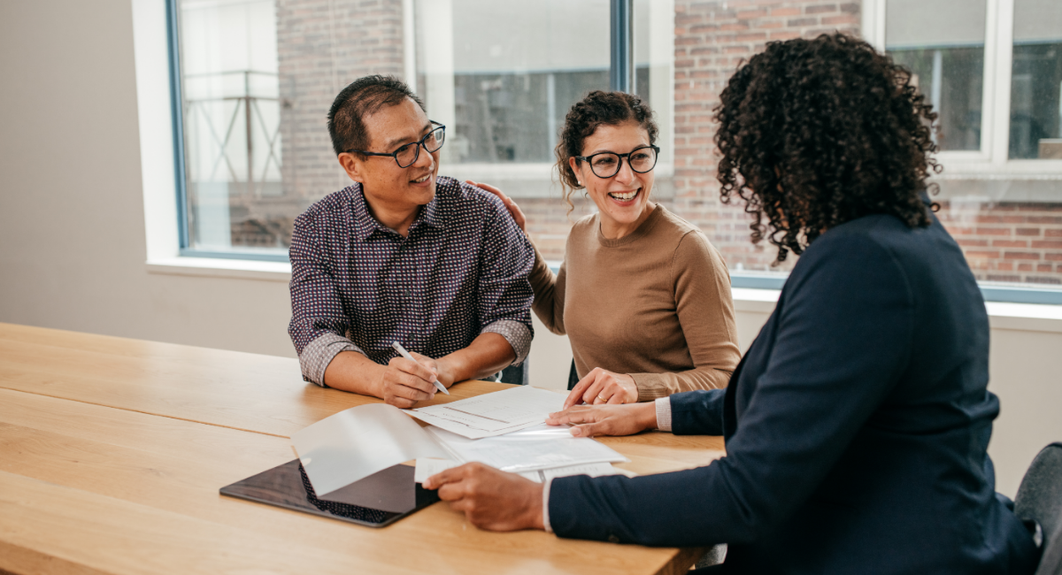 A landlord meeting with tenants to review property documents and discuss winter maintenance preparations in a bright office setting.