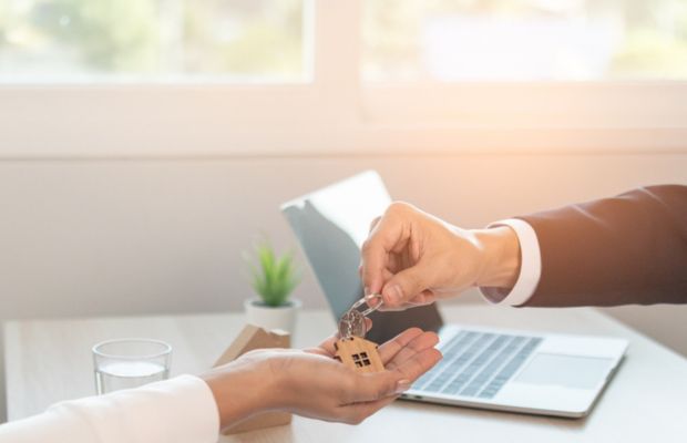 Handing over house key between two people.