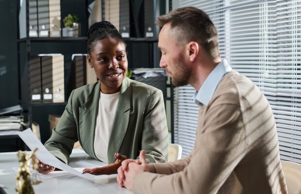 Estate agent and his client sitting at a table looking at documents
