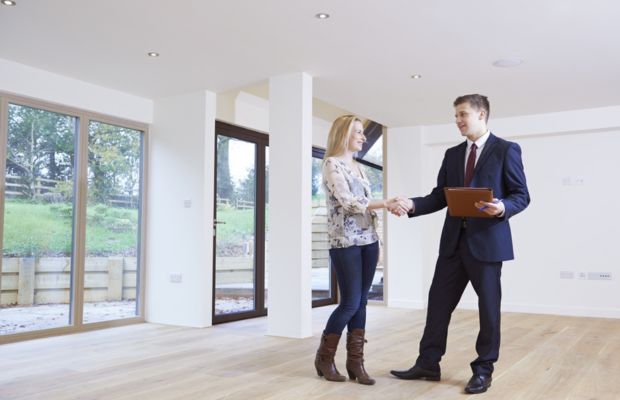 Man and woman shaking hands in empty room.