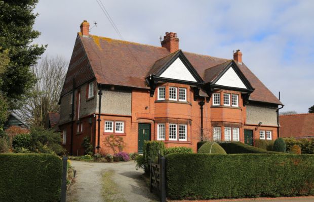 Two-story house with red brick and green doors.