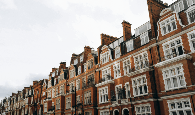 Row of traditional UK residential buildings under a cloudy sky, representing the UK housing market and future property outlook.