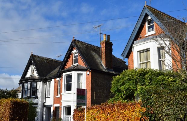 Three houses with varied architectural styles and greenery.