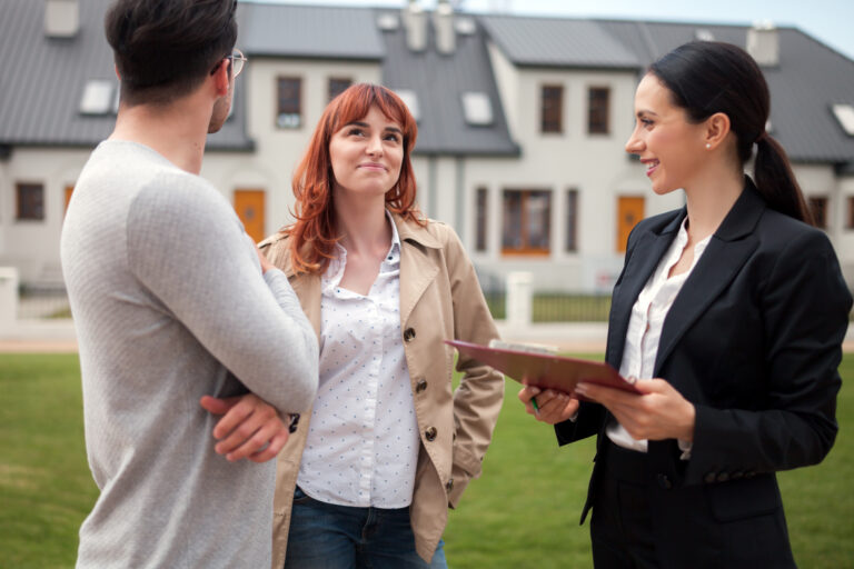 Homeowners speaking with an estate agent outside a modern housing development in Woking during the West Surrey unitary council transition in 2026