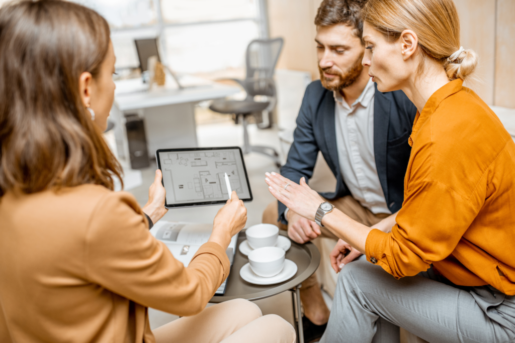 Letting agent showing property plans on a tablet to a couple, representing property management and landlord compliance in Stirling