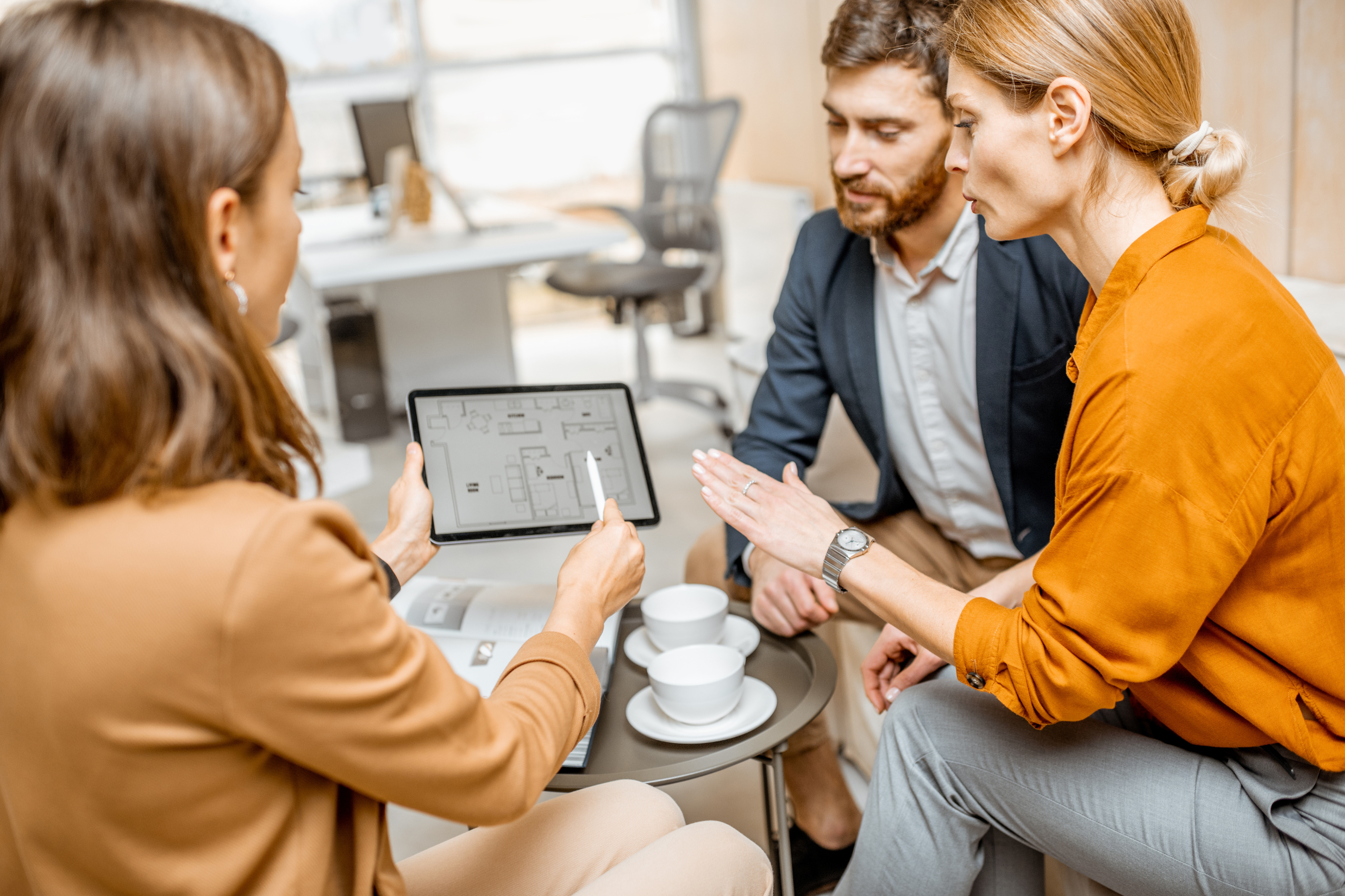 Letting agent showing property plans on a tablet to a couple, representing property management and landlord compliance in Stirling