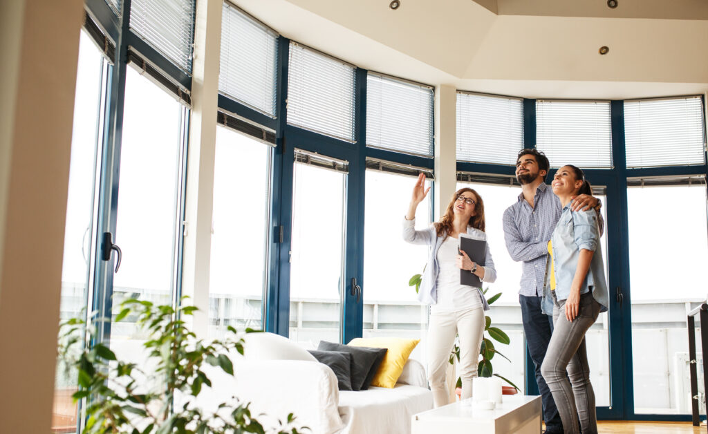 Property agent presenting a bright apartment to a couple, representing estate agents in Leamington Spa and town centre property demand