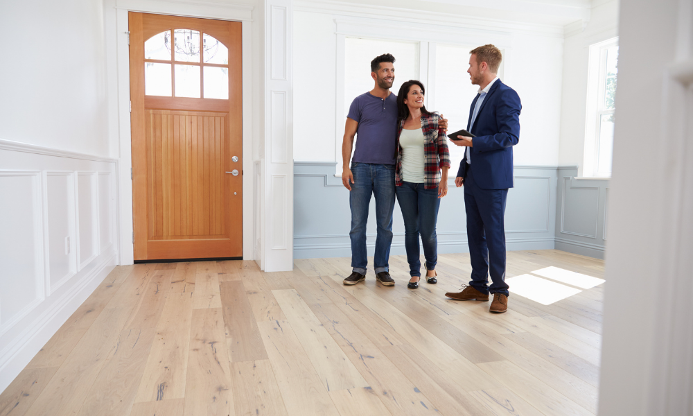 Estate agent discussing a property with tenants inside a rental home related to the Decent Homes Standard for private rentals.