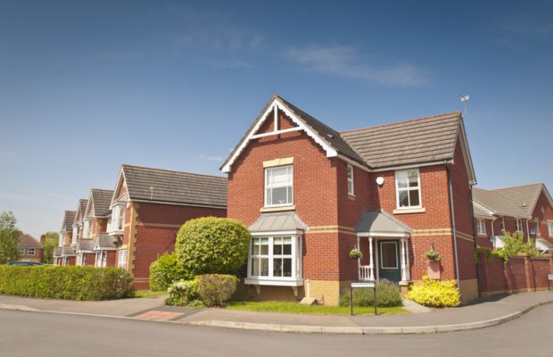 A red brick house surrounded by a white fence, showcasing a classic residential design.