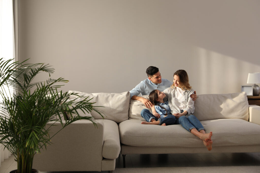 Family relaxing together on a sofa in a bright modern home representing family living in Stirling