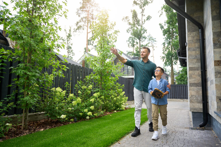 Father and son walking through a landscaped garden outside a modern family home