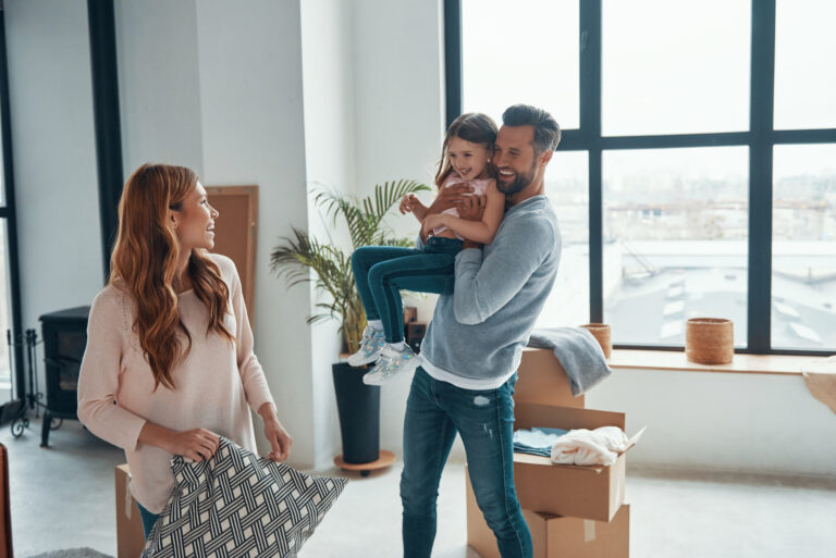 Family unpacking boxes and enjoying time together in a bright new home after moving