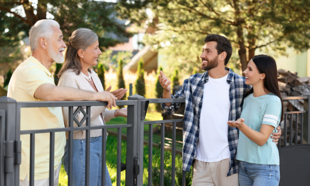 Two couples chatting over a garden fence in a peaceful residential neighbourhood
