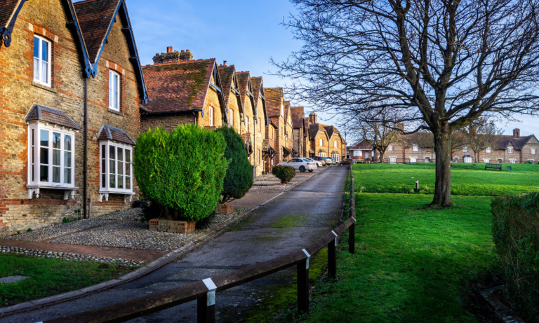 Row of traditional houses along a quiet street with green space and trees in West Oxford