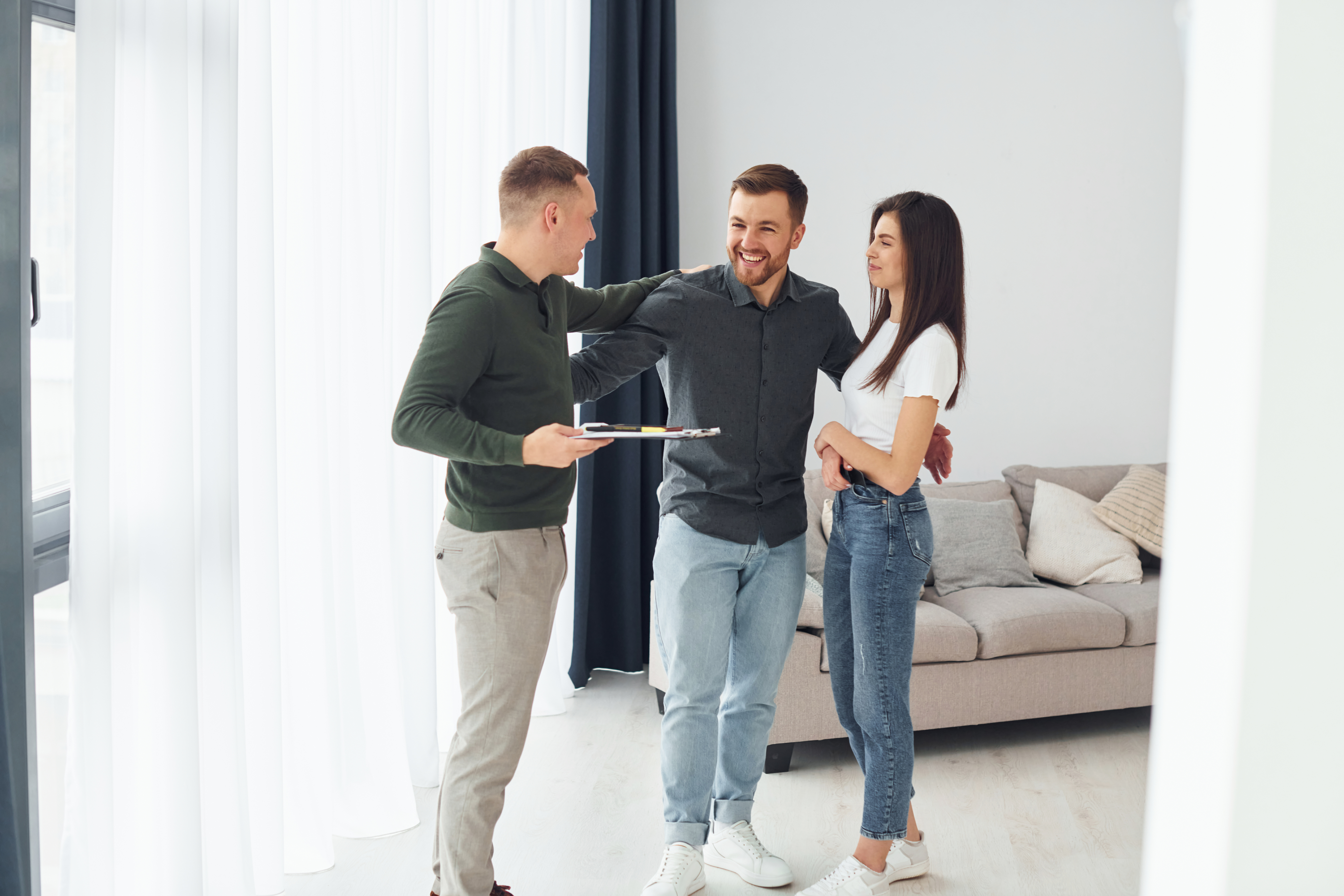 Letting agent showing a property to a couple while discussing rental management services in a bright living room