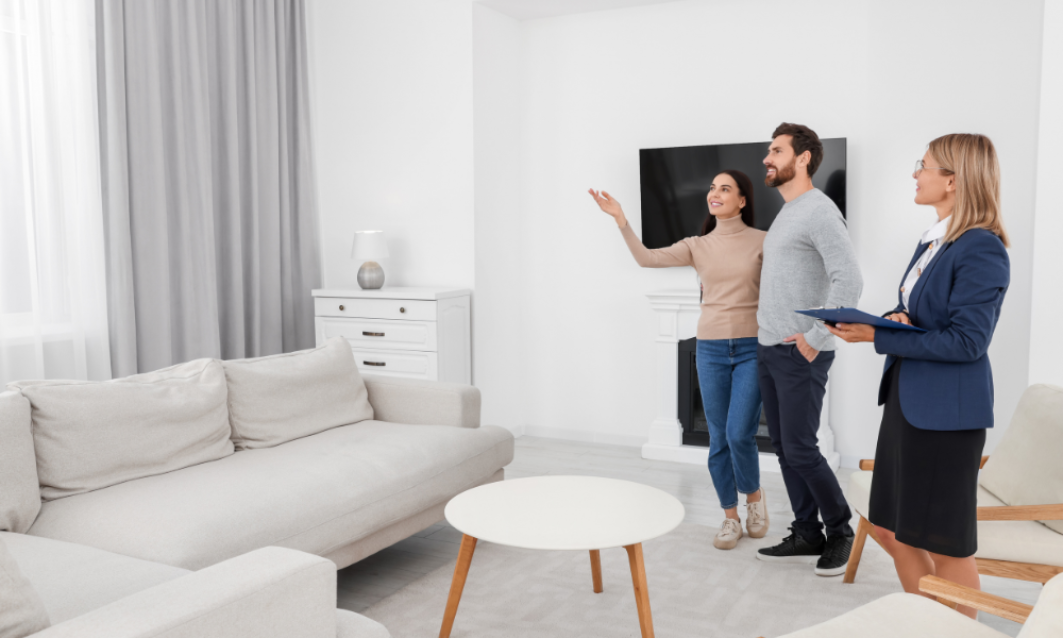 Letting agent showing a bright living room to a couple during a property viewing