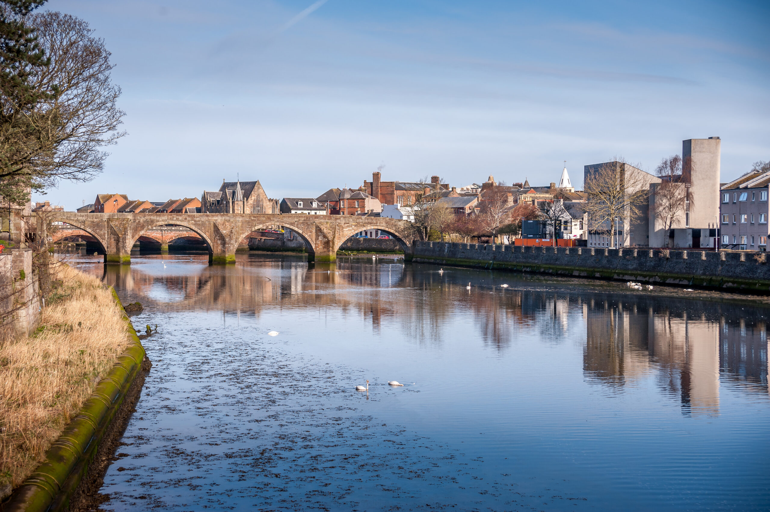 Scenic view of Ayr town centre with historic stone bridge over the River Ayr in Scotland.