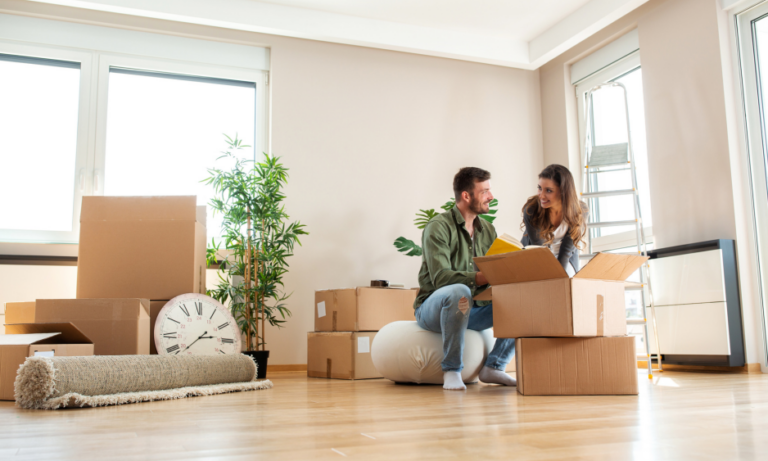 Couple unpacking boxes inside an empty property in Cardiff before renting or moving in.