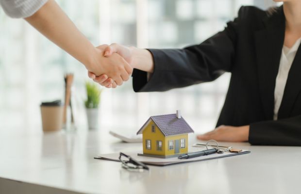 Handshake over a table with a model house.