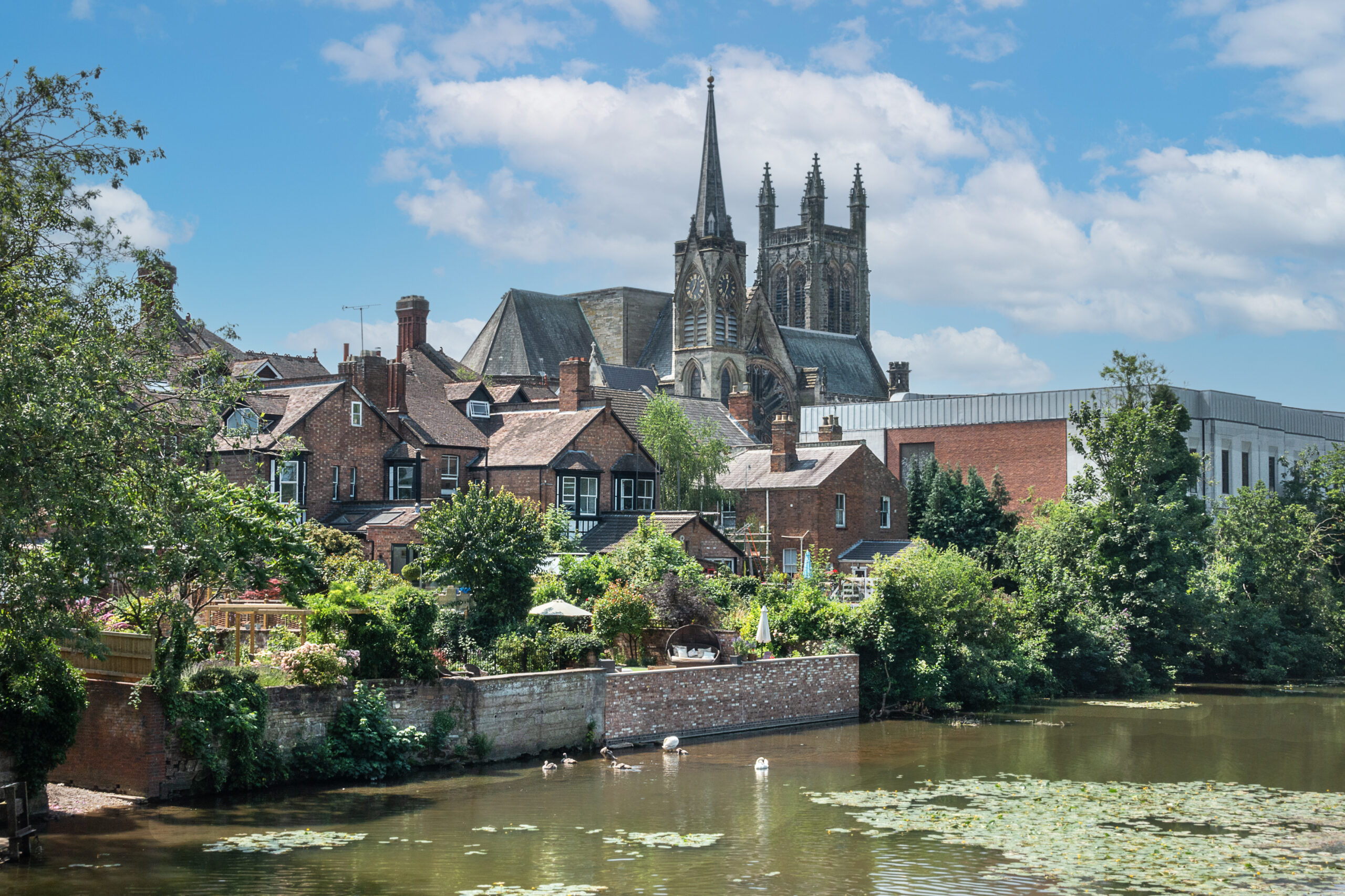 Scenic view of Royal Leamington Spa with residential homes and historic church buildings near the river.