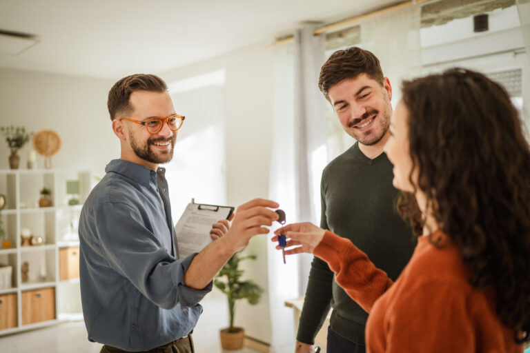 Estate agent handing over house keys to buyers during a property sale in Woking