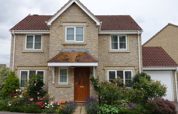 A house featuring a welcoming front door and a well-maintained front garden with various plants and flowers.