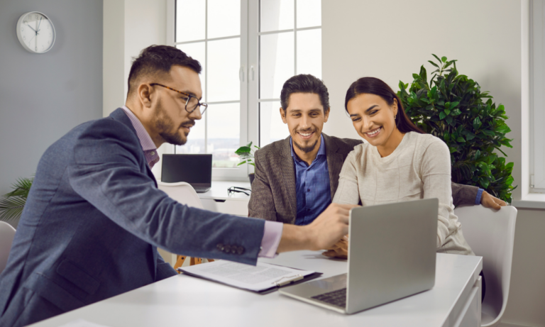 A property agent discussing information on a laptop with a smiling couple, representing expert advice for buyers, renters, sellers and landlords exploring the Great Baddow CM2 property market.