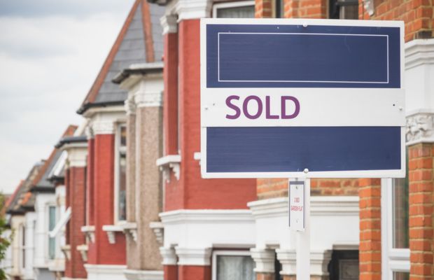 A sold sign stands prominently in front of a row of houses, indicating successful real estate transactions.