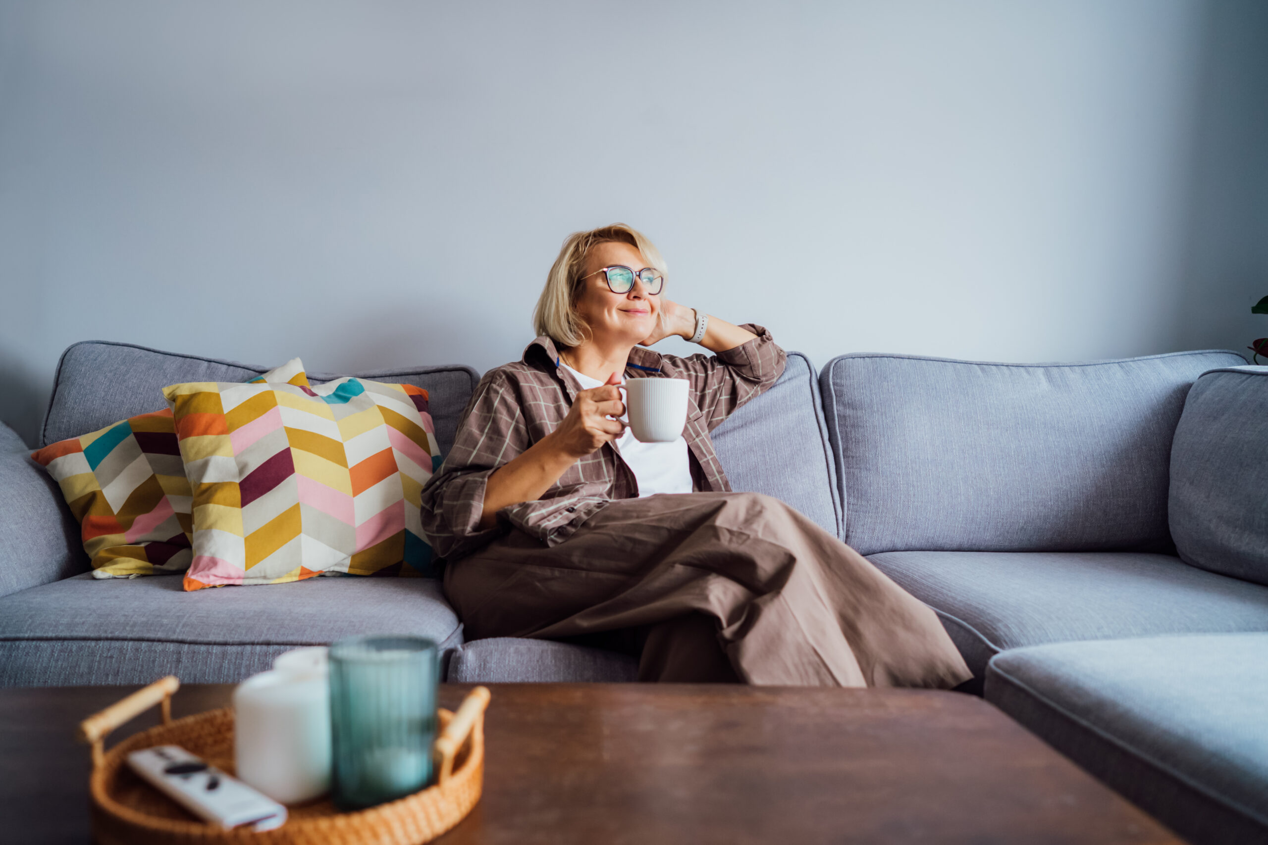 Woman relaxing on a sofa in a bright living room, reflecting comfortable home living and the lifestyle appeal of selling property in Barbourne and Claines.
