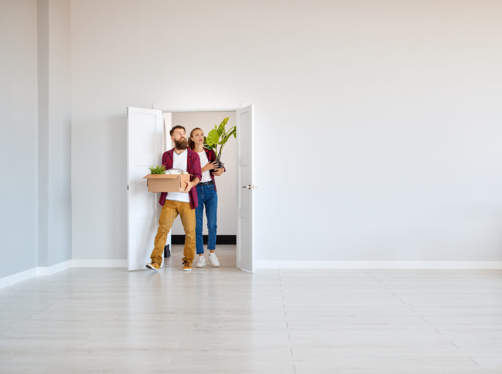 Couple carrying moving boxes into a bright empty home, reflecting the excitement of buying property in B14 and Yardley Wood.