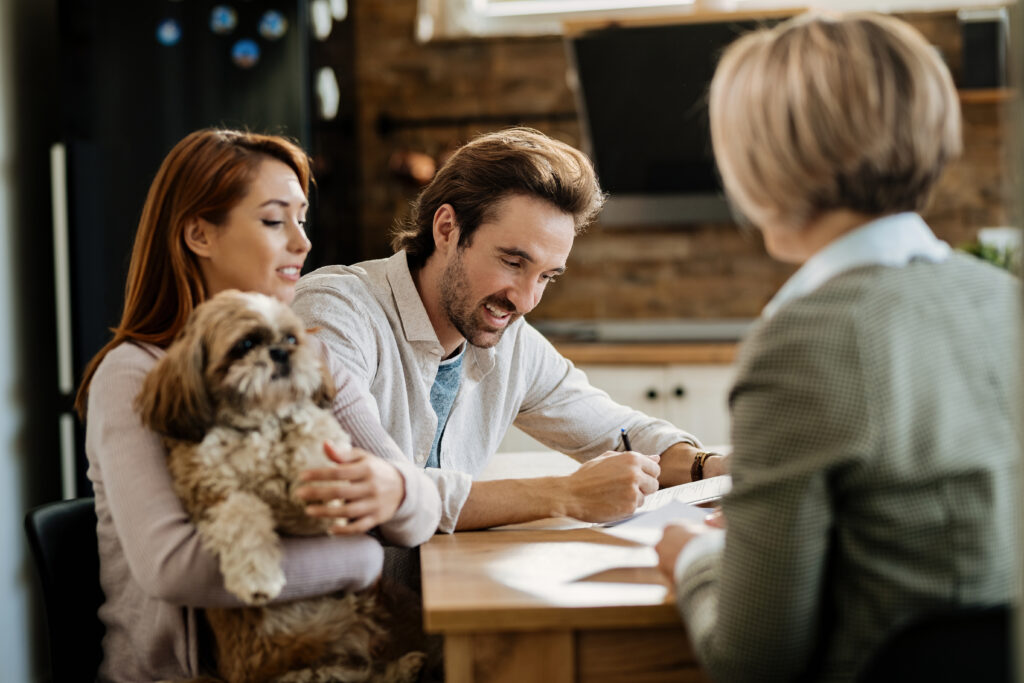 Couple meeting with an estate agent to discuss selling their home in Ayr, with their dog beside them.
