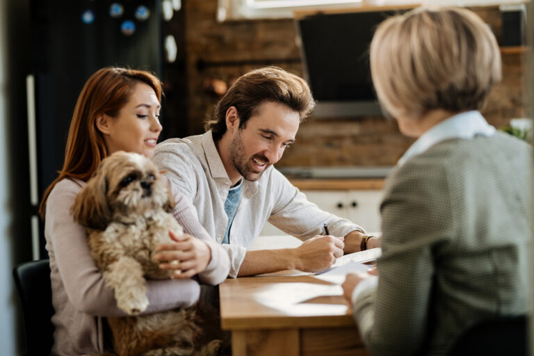 Couple meeting with an estate agent to discuss selling their home in Ayr, with their dog beside them.