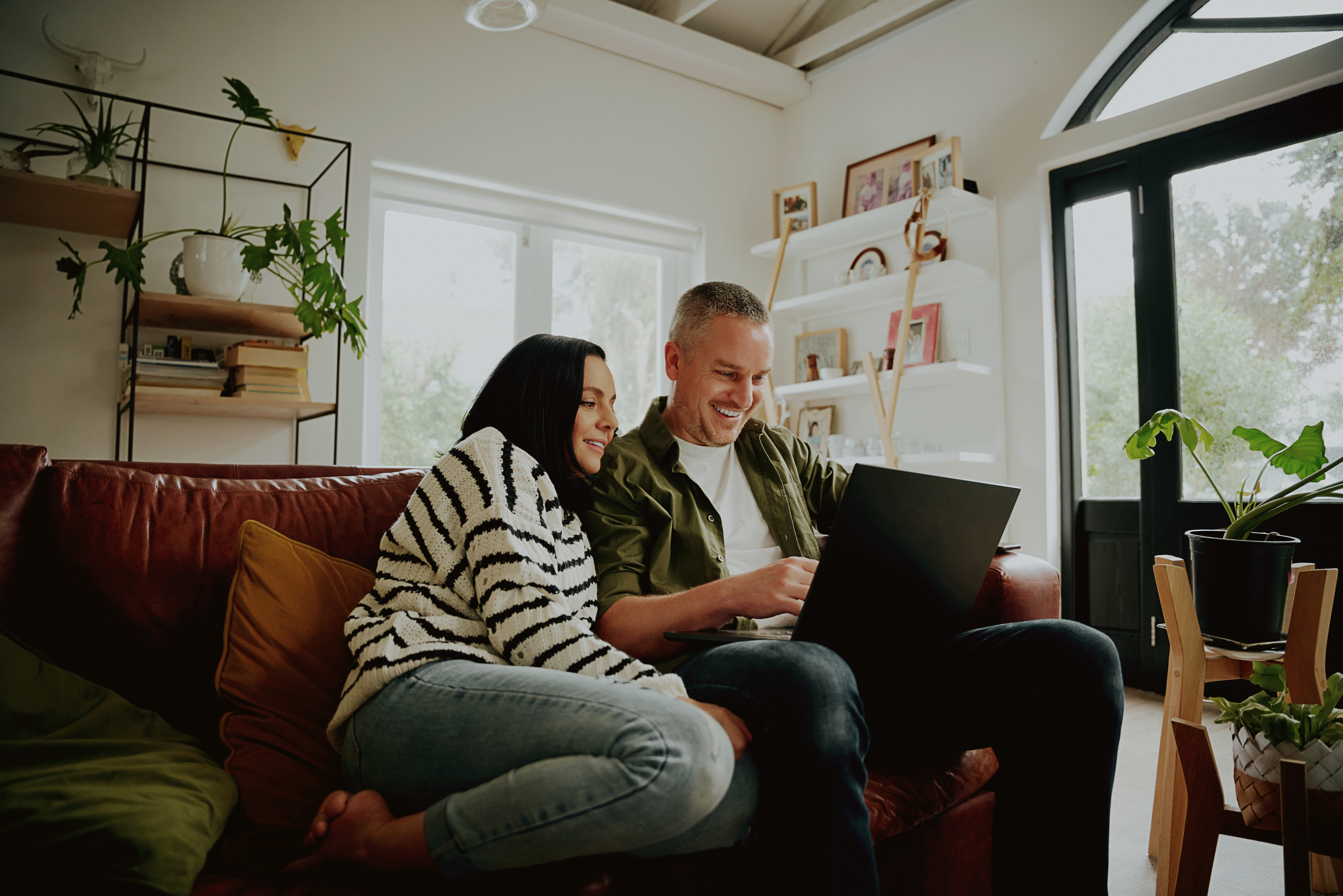 A couple researching homes together on a laptop in their living room while planning a move to AB22 Aberdeen.