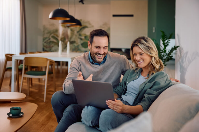 A couple sitting together on a sofa using a tablet to research homes in Iffley OX4, Oxford.