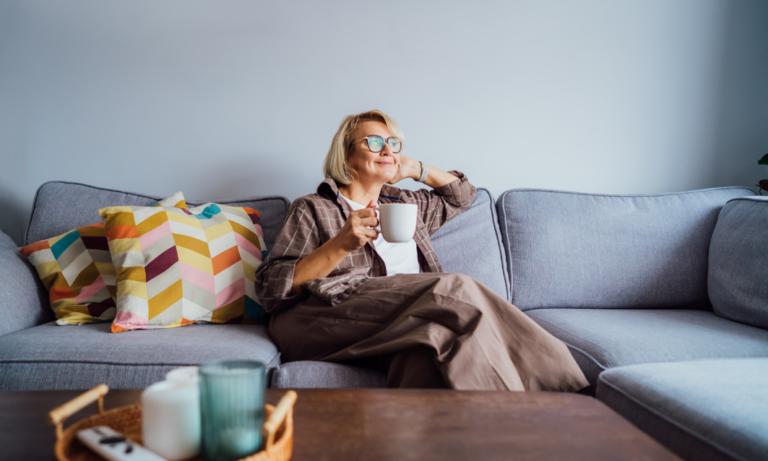A woman relaxing with a cup of coffee in her modern living room in Warndon Villages, Worcester.