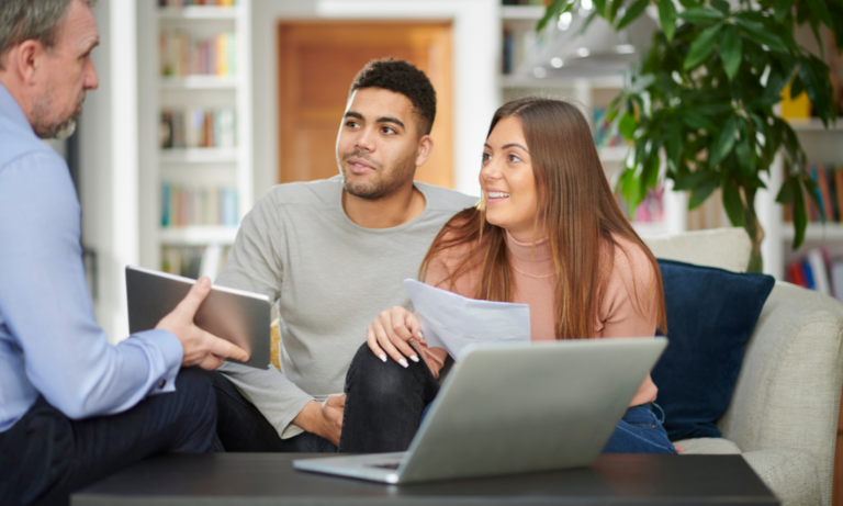 A couple discussing property details with an estate agent during a home consultation in Longton ST3.