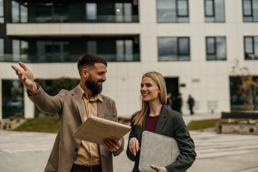 Letting agent discussing investment opportunities with a landlord outside a modern residential development in Uckfield.