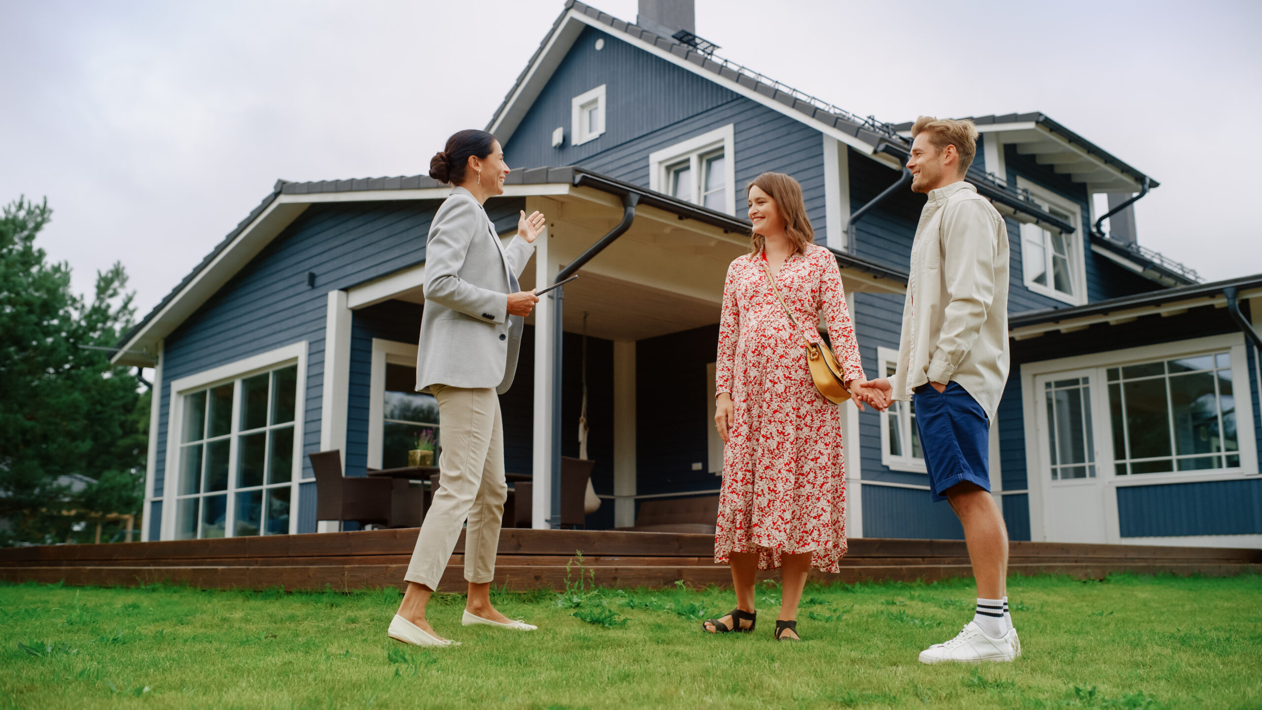 Estate agent speaking with a couple outside a modern family home during a property viewing in Warndon Villages.
